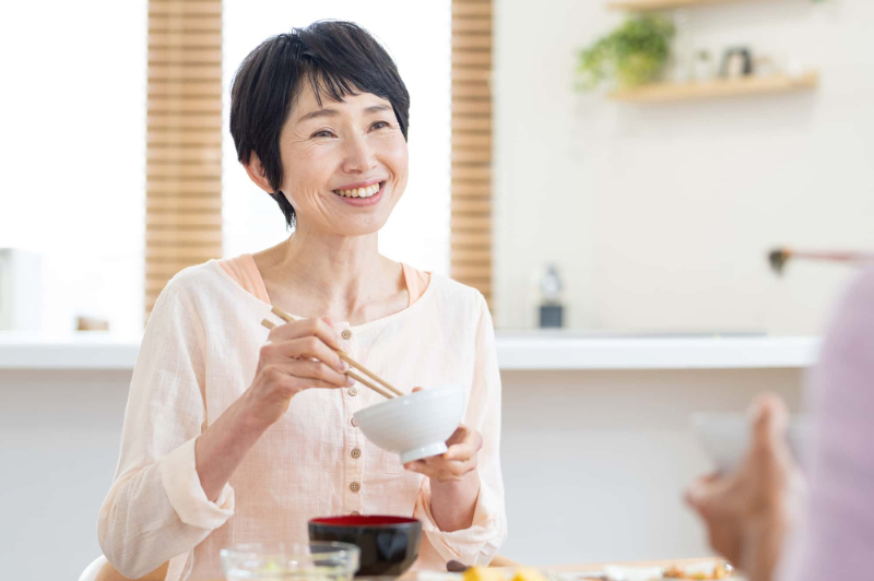 根管治療をして笑顔で食事をする女性