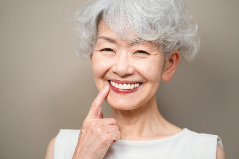 自費診療の入れ歯を装着して笑顔を見せるシニア女性