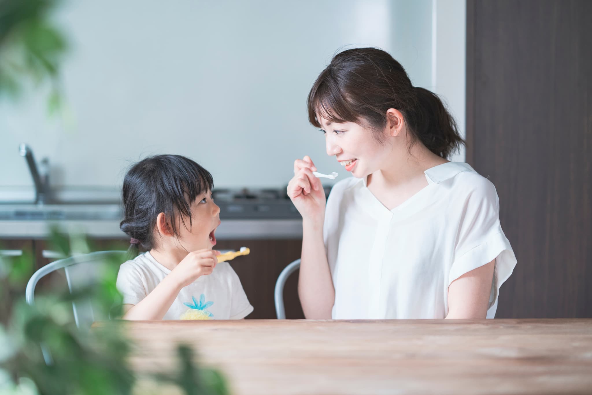 向かい合って歯磨きをする親子