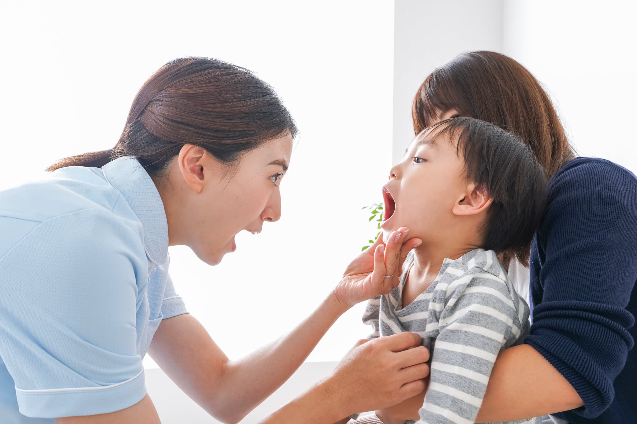 歯医者で虫歯のチェックをする子どもと歯科医師