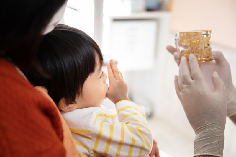 歯医者を受診する指しゃぶりする子どもと母親