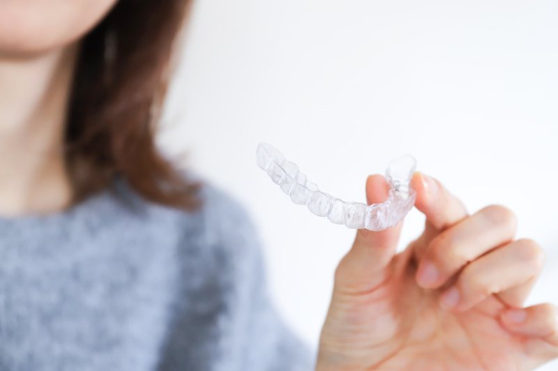 マウスピースタイプのリテーナーを片手で持つ女性