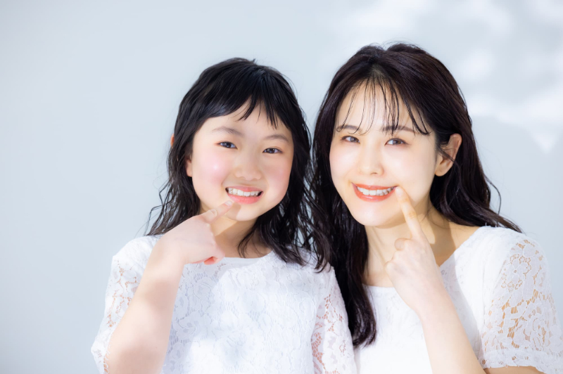 床矯正で綺麗になった歯を指さしてほほ笑む親子
