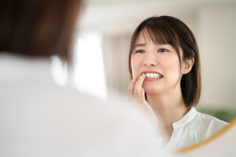 しみる歯を鏡で確認する女性